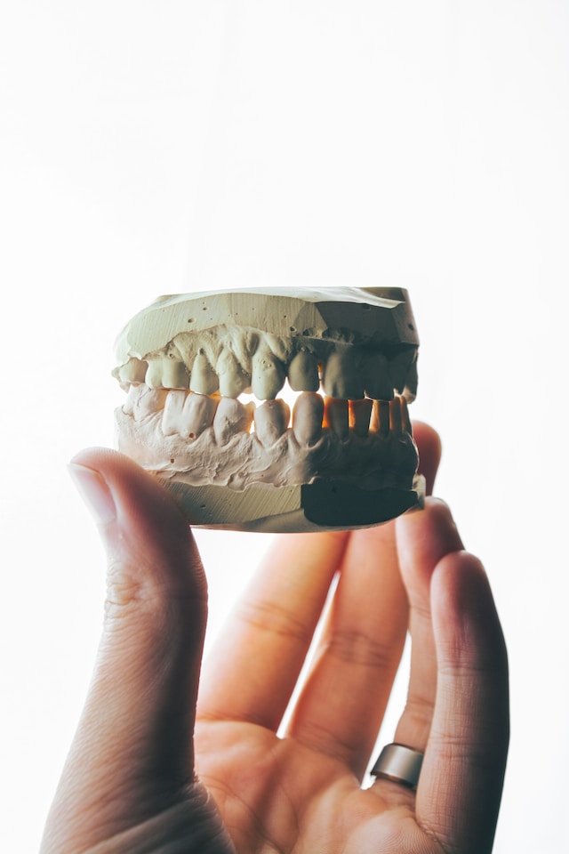 A hand holds a dental cast in an attempt to convey full mouth reconstruction