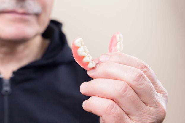 A man holds a partial denture after visiting a dentist in Fairfield, CT