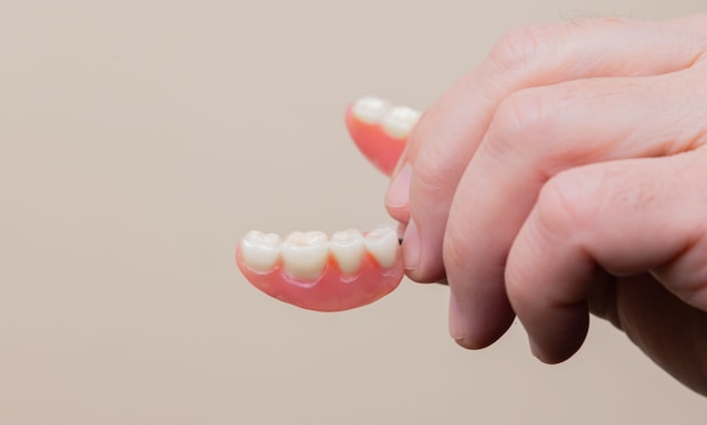 A close-up image of a hand holding partial dentures in Fairfield, CT