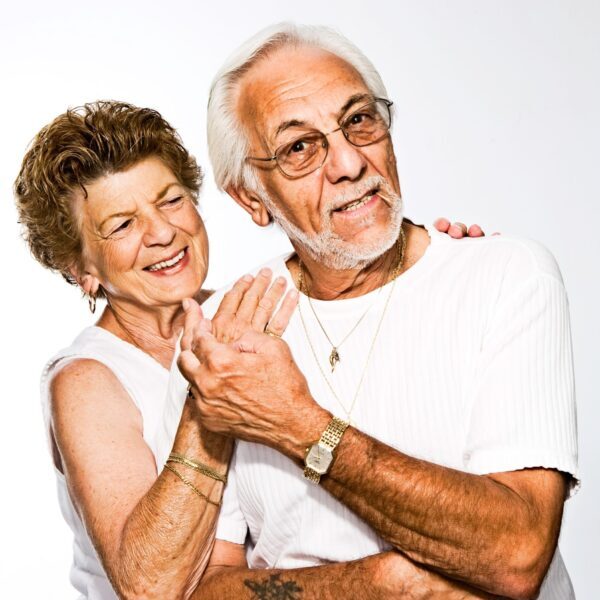 An older white couple embraces and smiles widely