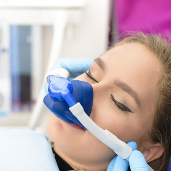 Woman receive nitrous oxide sedation via a mask over her nose