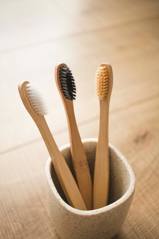 Three toothbrushes sit in a ceramic cup