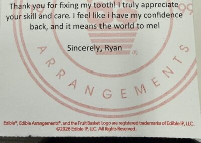 Thank-you card from Ryan to the dental team reading: 'Dear All, Thank you for fixing my tooth! I truly appreciate your skill and care. I feel like I have my confidence back, and it means the world to me! Sincerely, Ryan' with a pink Edible Arrangements logo in the background.